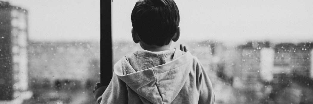 Backview of child waiting by a glass window