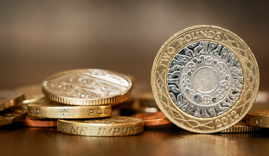 A selection of British coin currency scattered on a wooden table