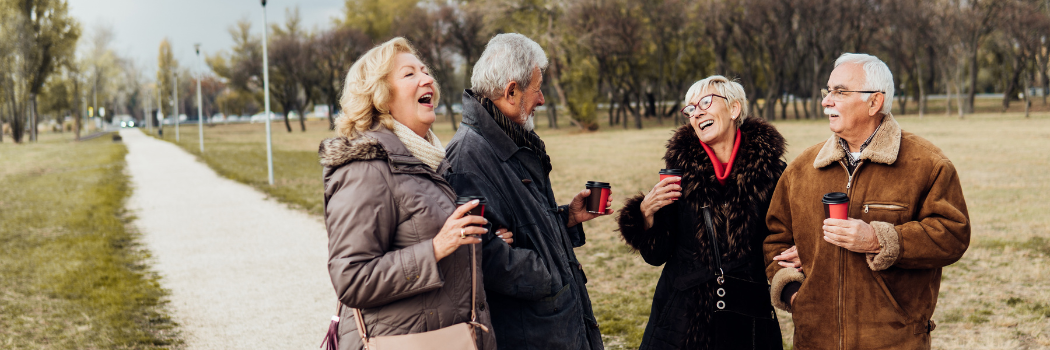 four people drinking coffee and laughing outdoors