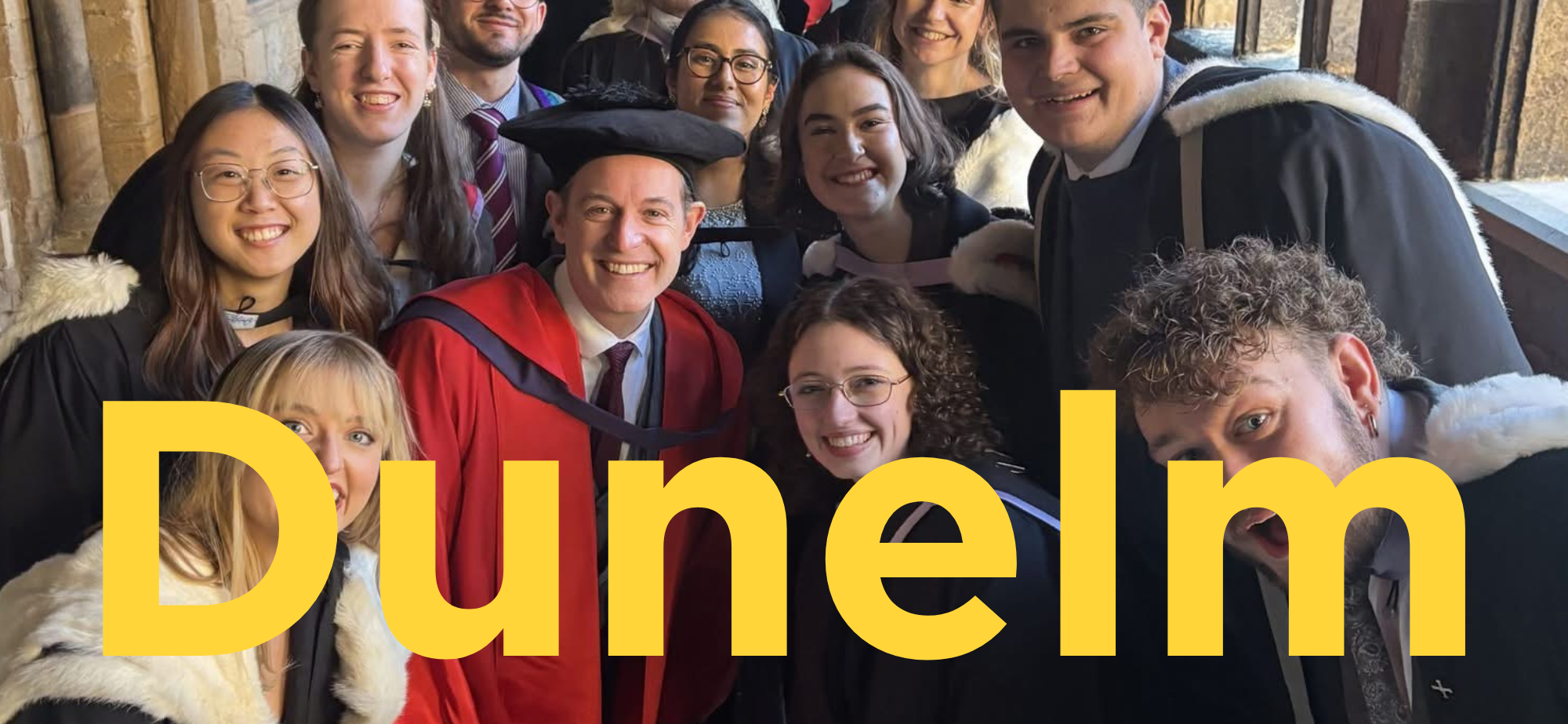 Matt Baker in hon grad gowns with a group of students