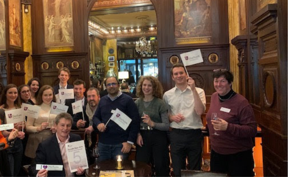 A large group of alumni students holding university flags