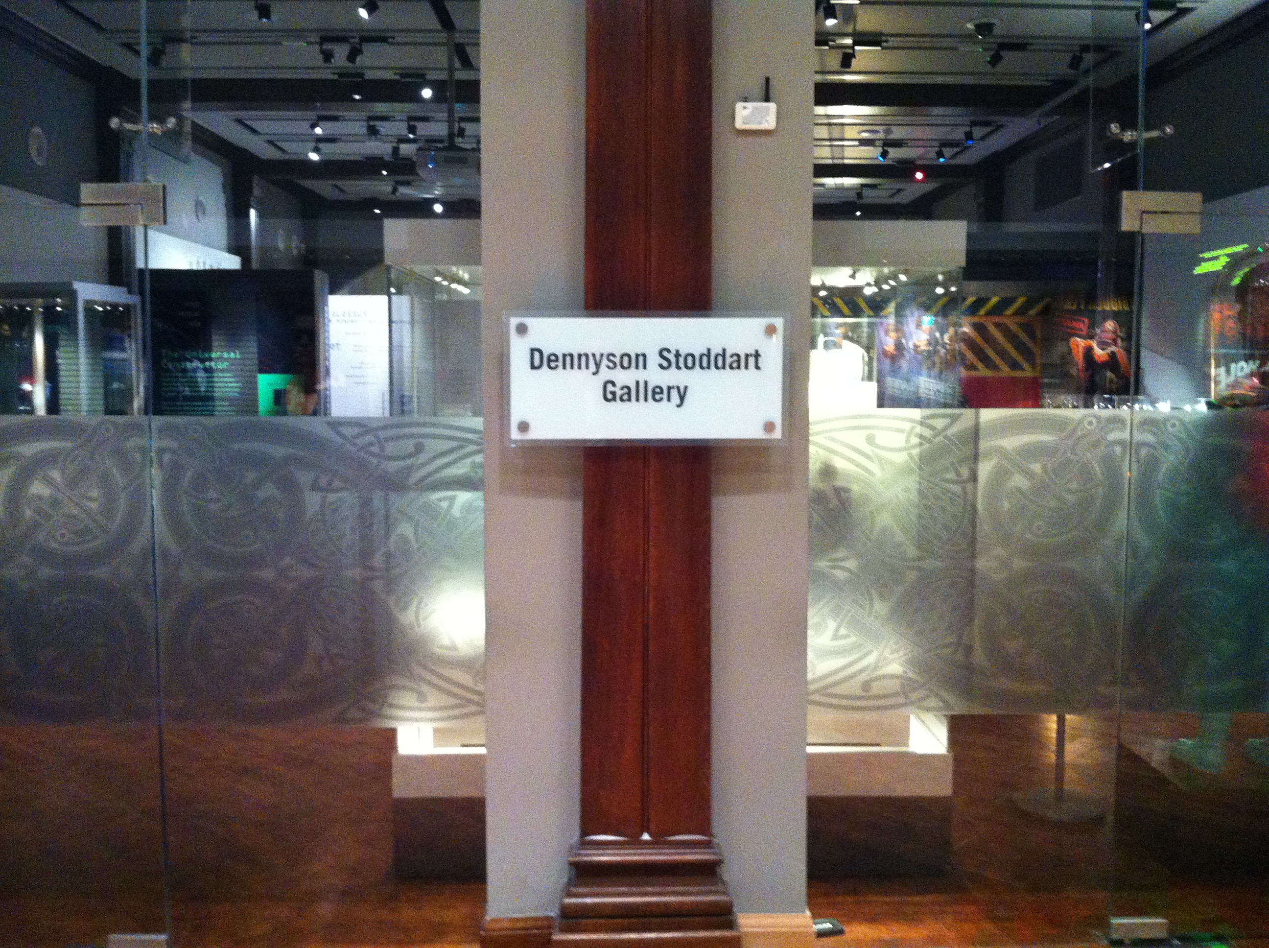 Image shows a plaque on a glass door displaying the name 