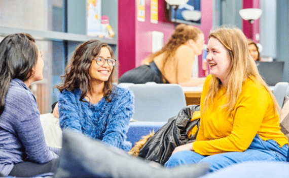 Three female students chatting on a couch