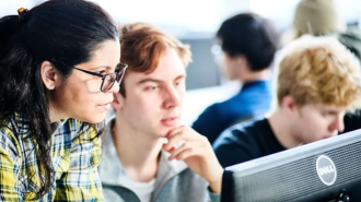 two students and academic looking at computer