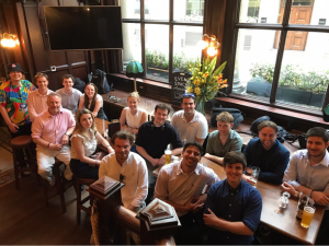 A group of alumni at an event, seated around a table with Rob Lynes