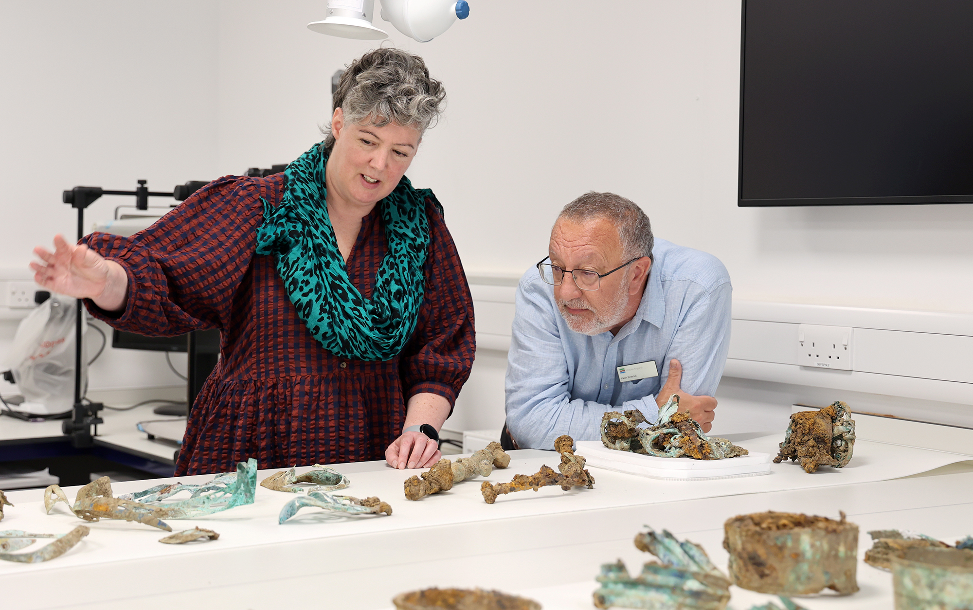 Two people looking over some of the artefacts which form The Melsonby Hoard. From left to right: Dr Sophia Adams, Curator, The British Museum; and Dr Keith Emerick, Inspector of Ancient Monuments, Historic England.
