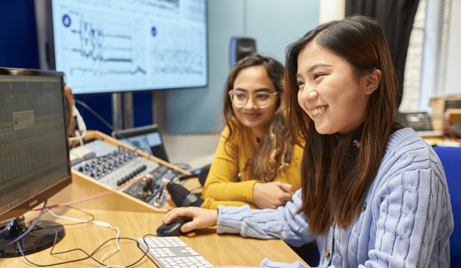 Two female students at a computer with screens