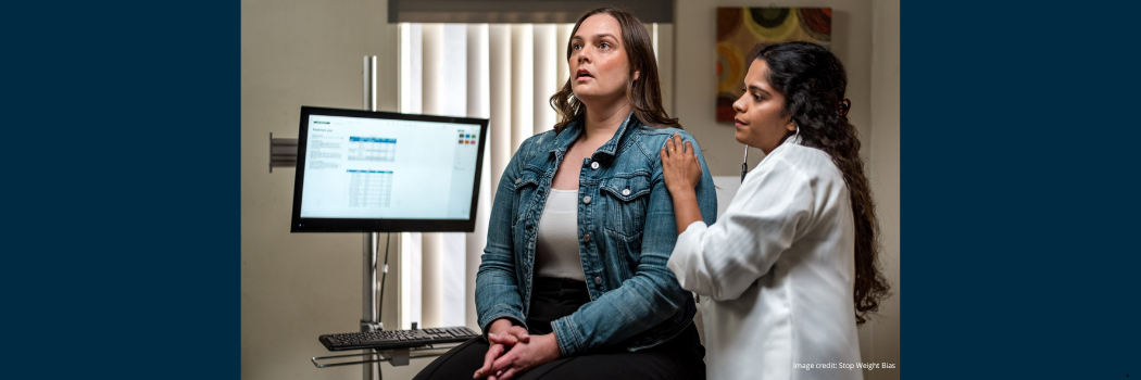 Patient sat in medical consultation with healthcare practitioner to their left listening with a stethoscope