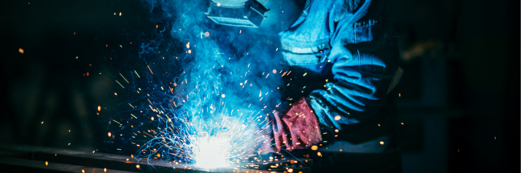 A welder at work wearing a visor with sparks showing.