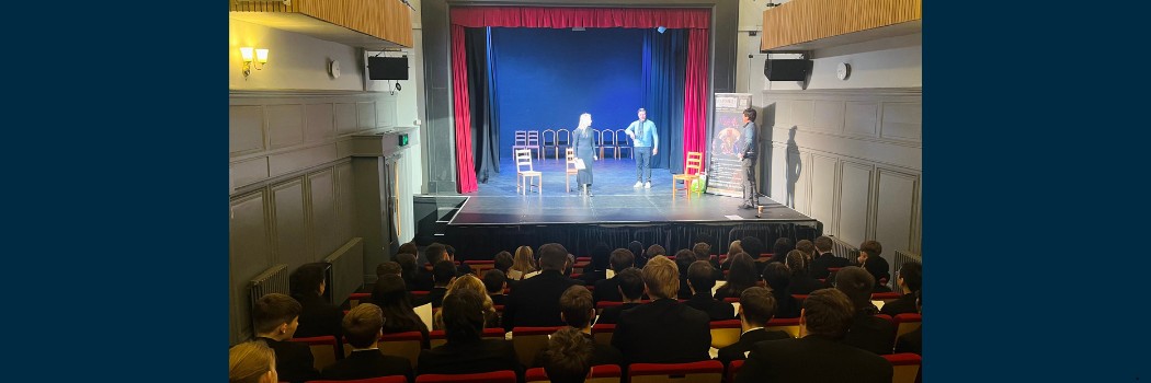 Local school pupils sat in the auditorium of Sir Thomas Allen Assembly Rooms Theatre with actors on stage performing a scene from a Shakespeare play. Image credit Paul G Clark