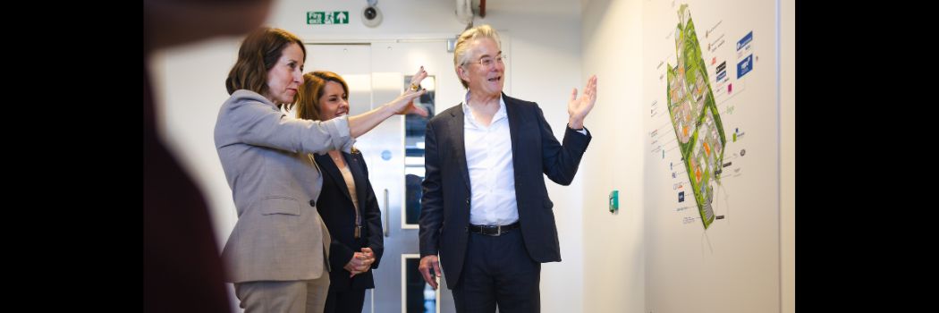 Two women and a man looking at designs on a board on a wall