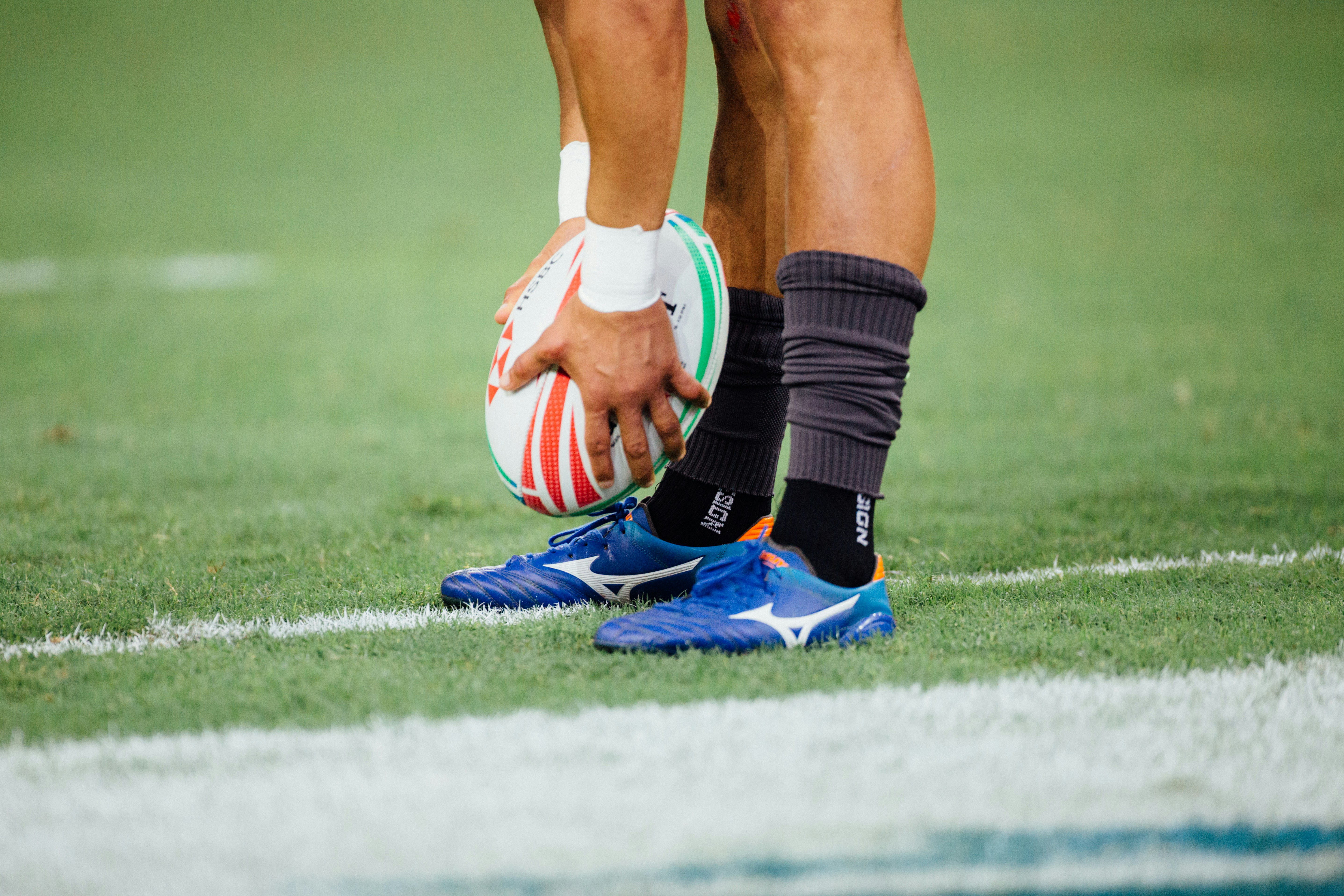Close-up of a male rugby player holding a rugby ball by their feet