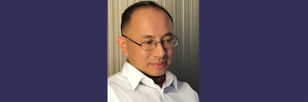 Head and shoulders picture of a man wearing glasses and looking slightly downwards and off to the side of the camera.