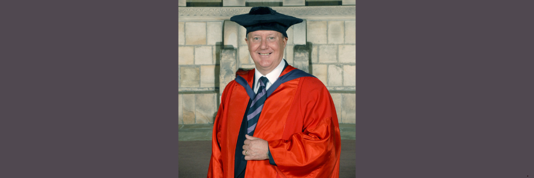 Kenneth Calman wearing a red graduation robe