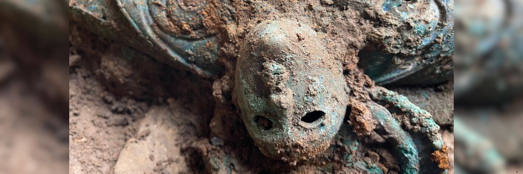 A metal face peering out of the mud during the Melsonby Hoard excavation
