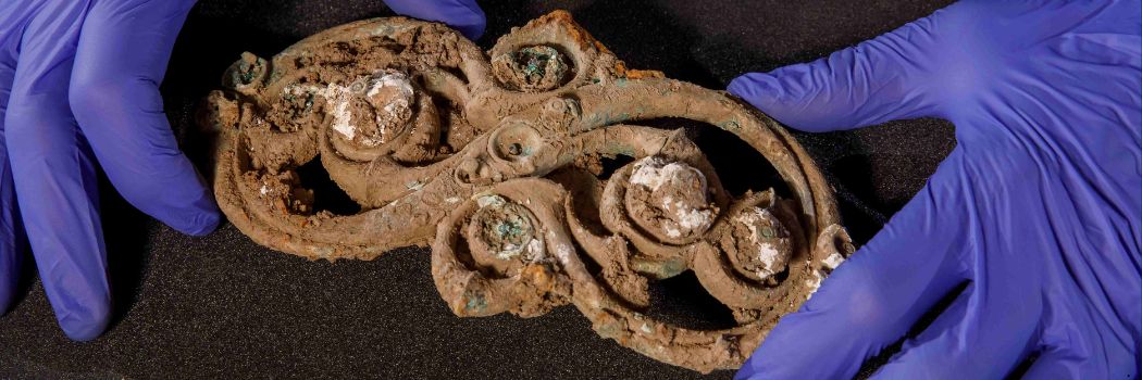 Close up of on ornate iron age artefact being held in a person's hands.