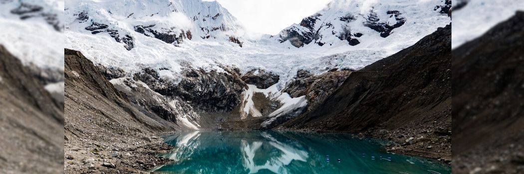 A mountain glacier running into water.