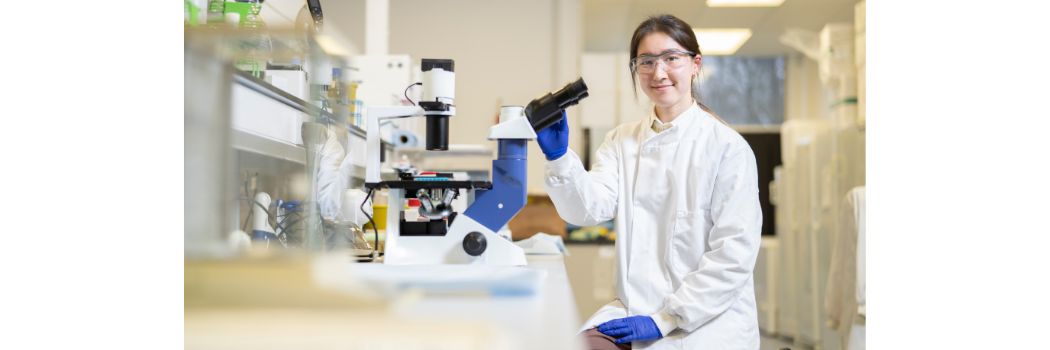 Woman in lab coat holding microscope-like device