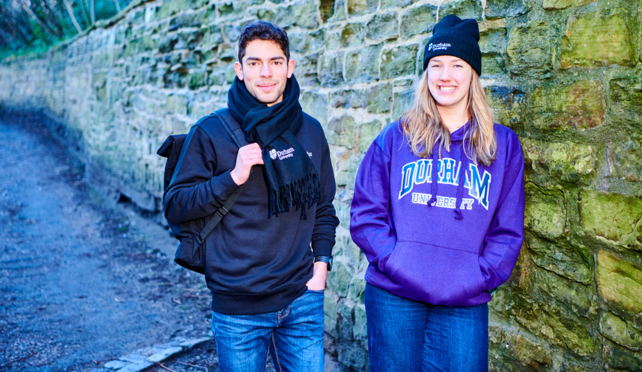 Three students walking and chatting with red brick buildings in the background