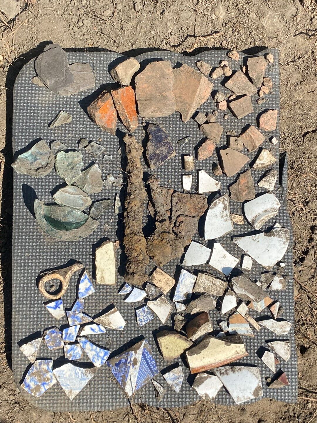 Black textured foam mat with an array of archaeological finds on top of it.