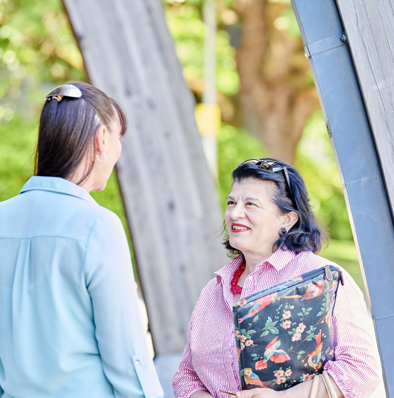 Two women stand smiling and talking