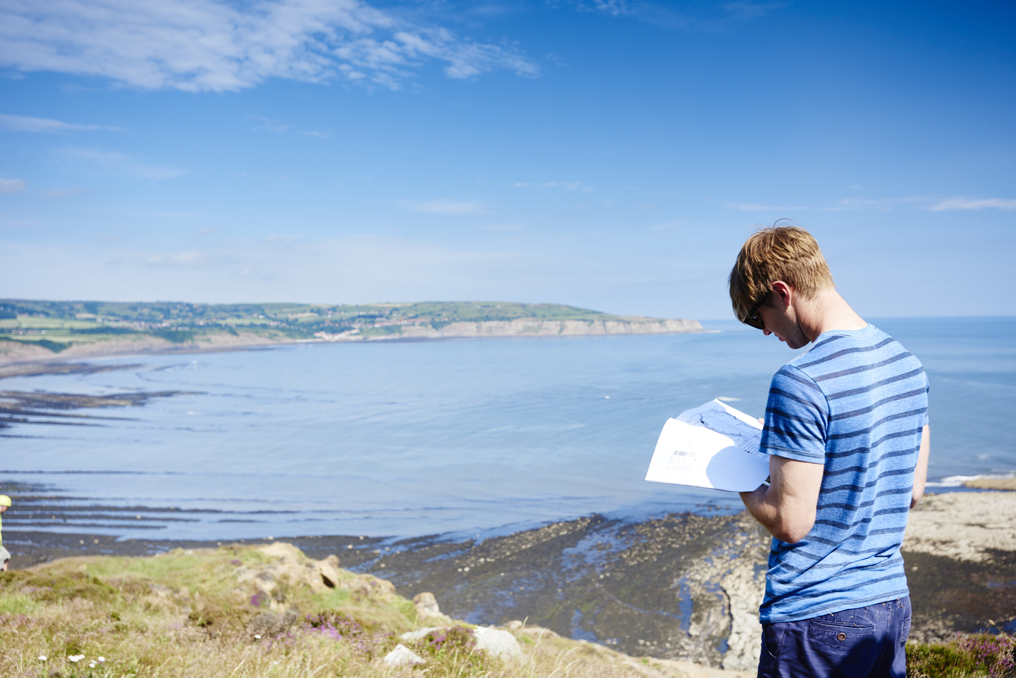 Man reading while overlooking sea