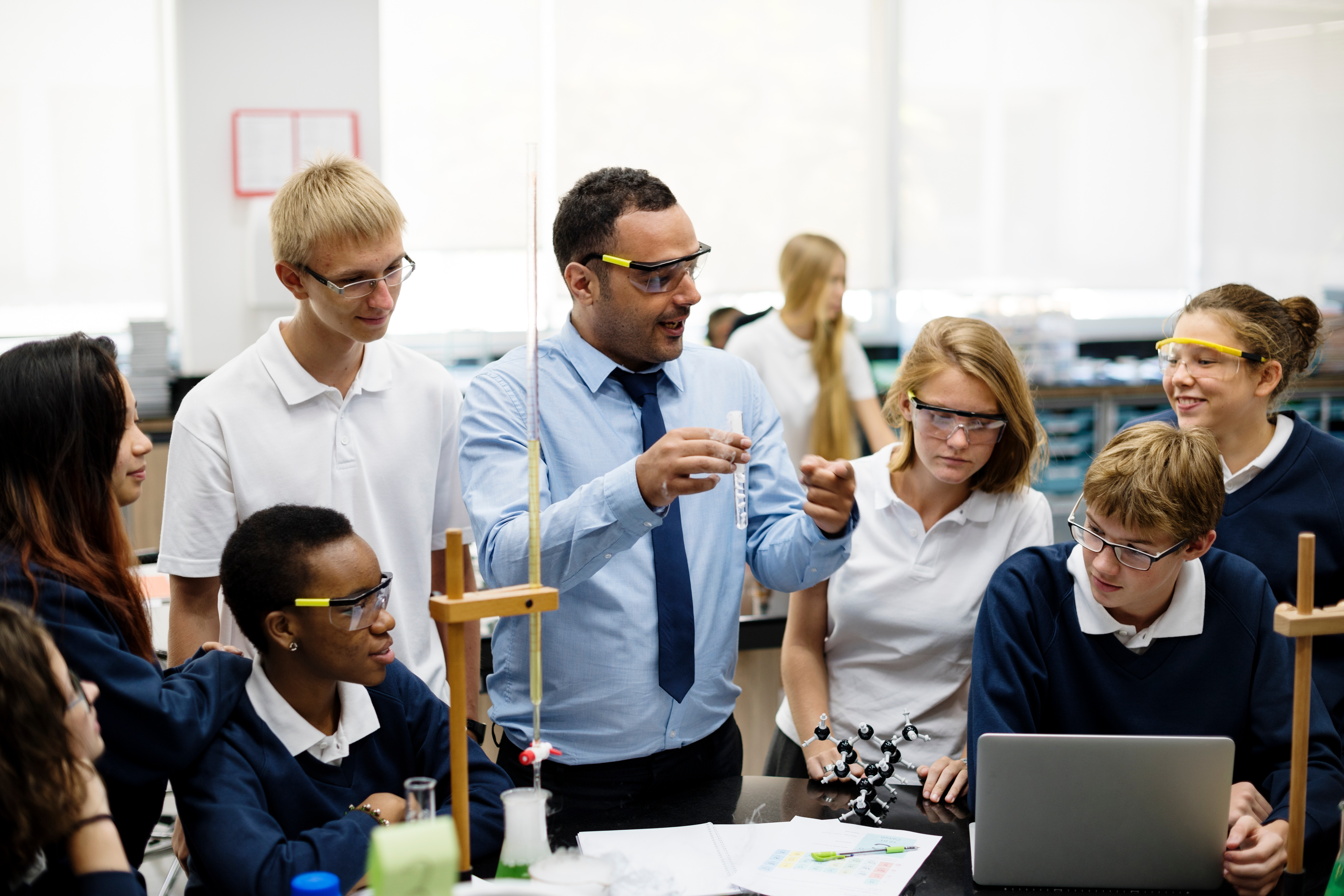 Science teacher demonstrating an experiment to a group of secondary school pupils.