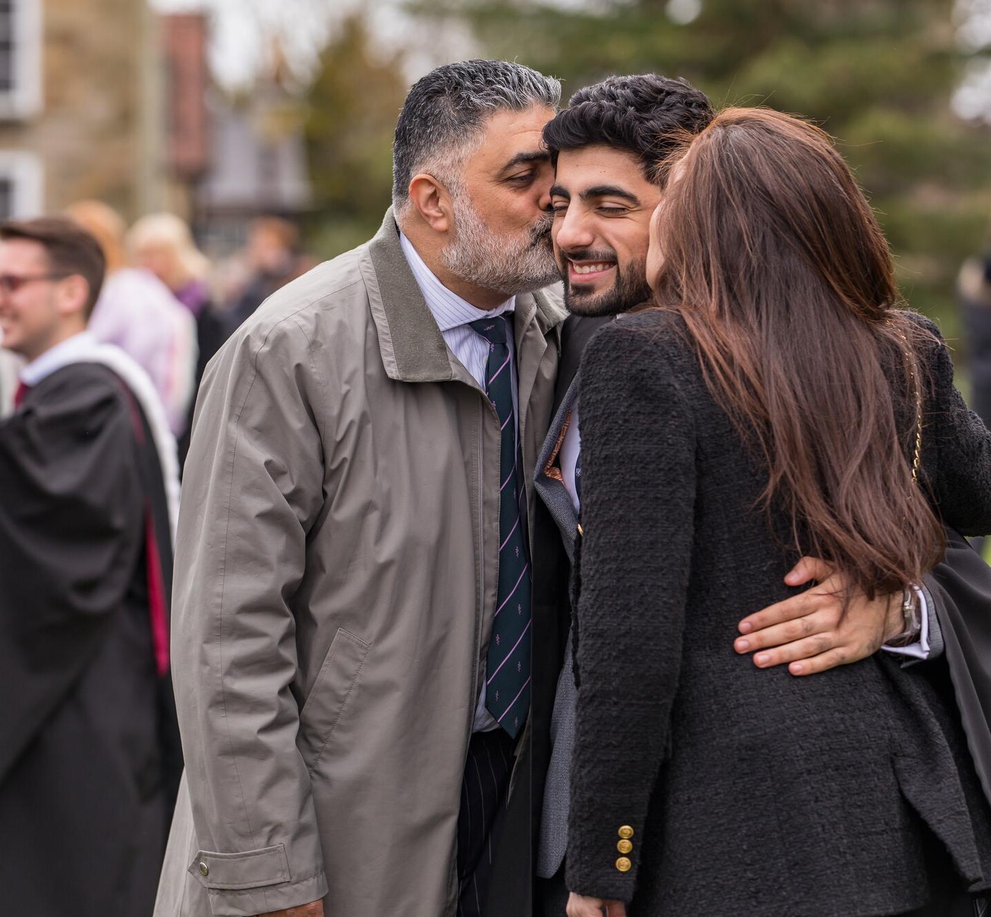 A graduating student being embraced by their guests