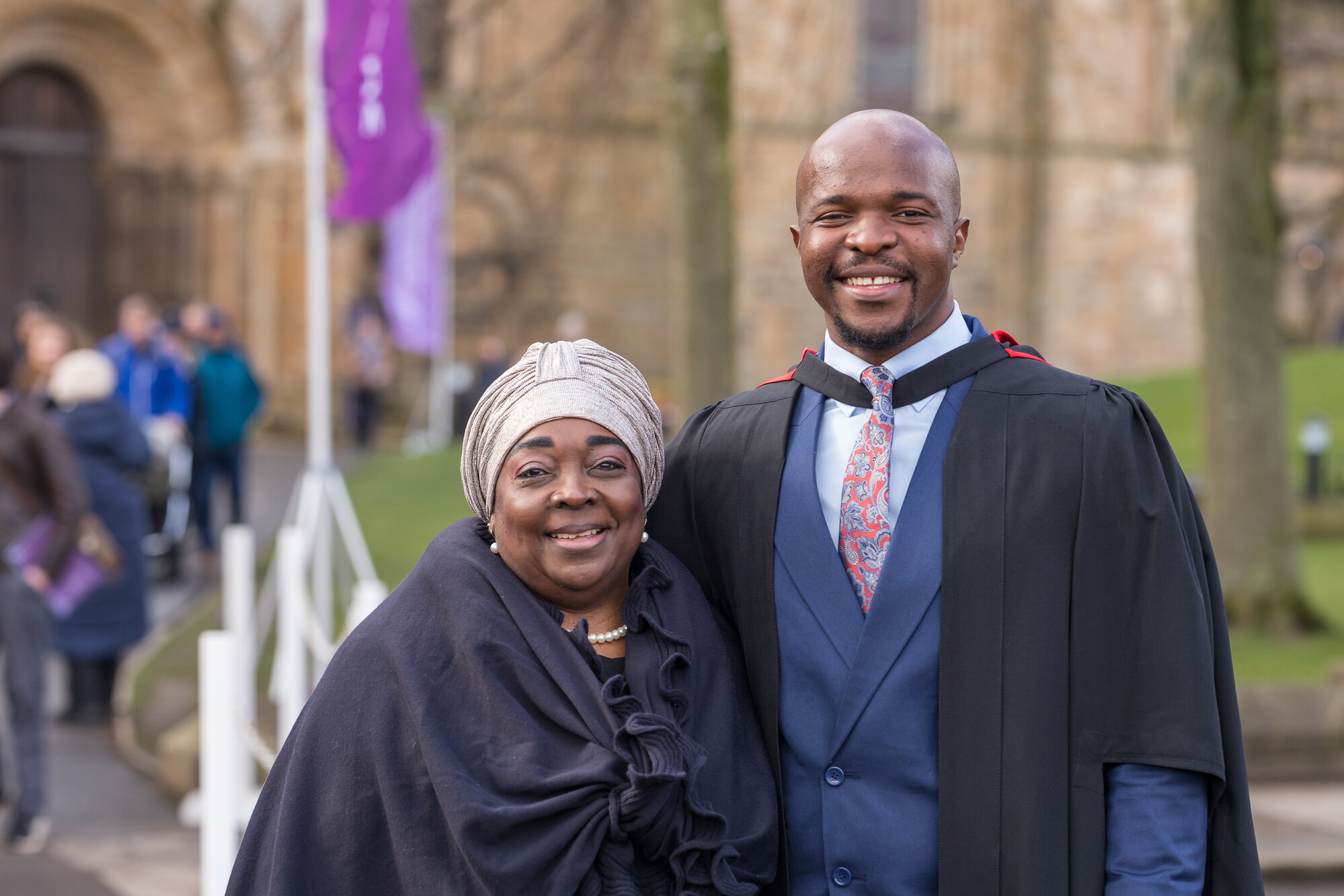 Graduate in robes smiling with guest
