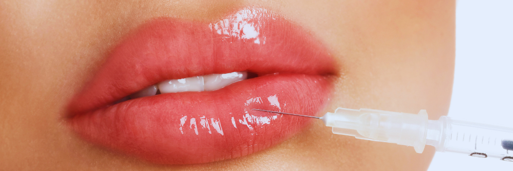 A closeup of a woman's lips with a needle injecting fluid