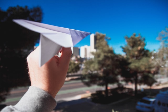 A hand launching a paper aeroplane