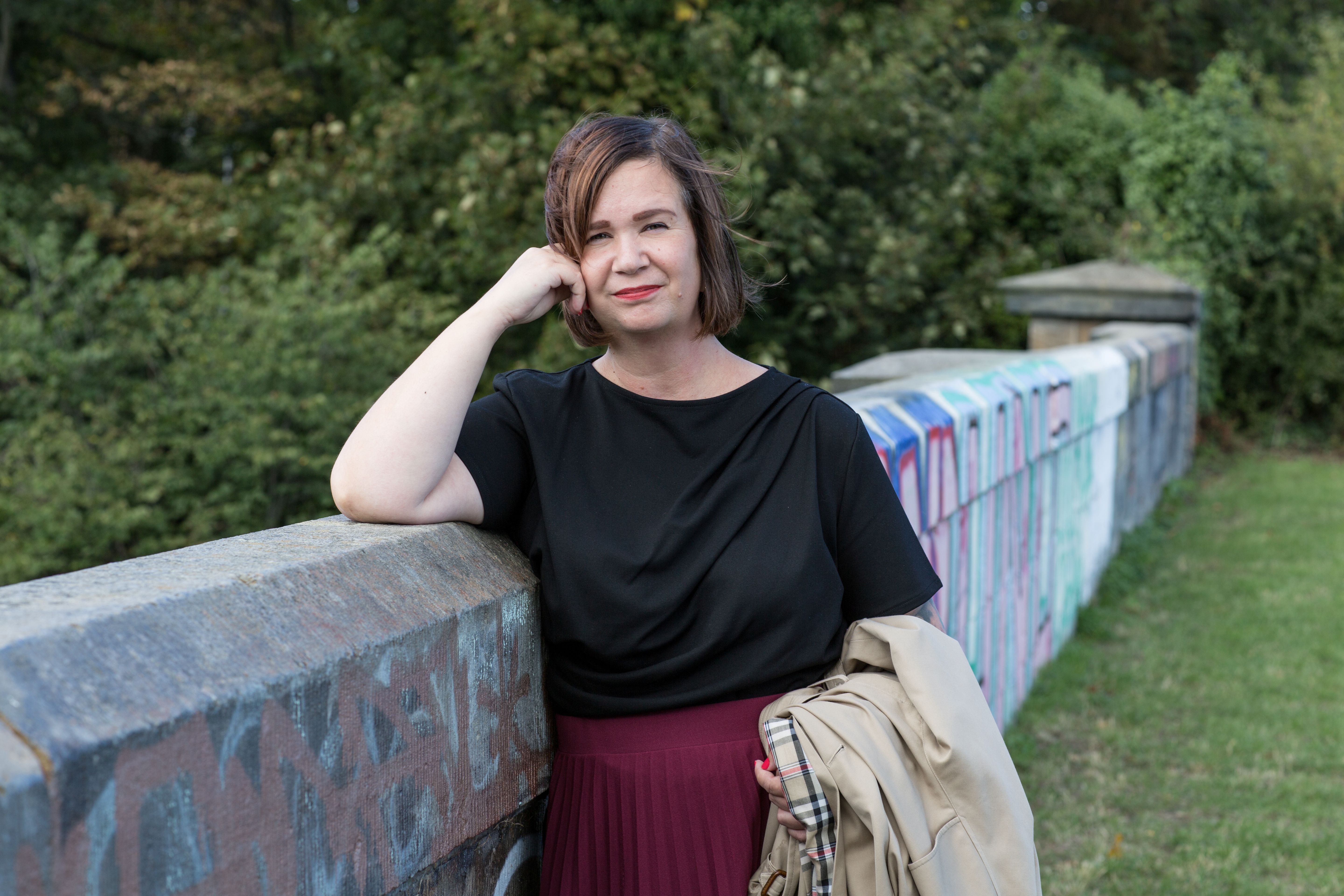 Paula mid shot leaning on stone bridge