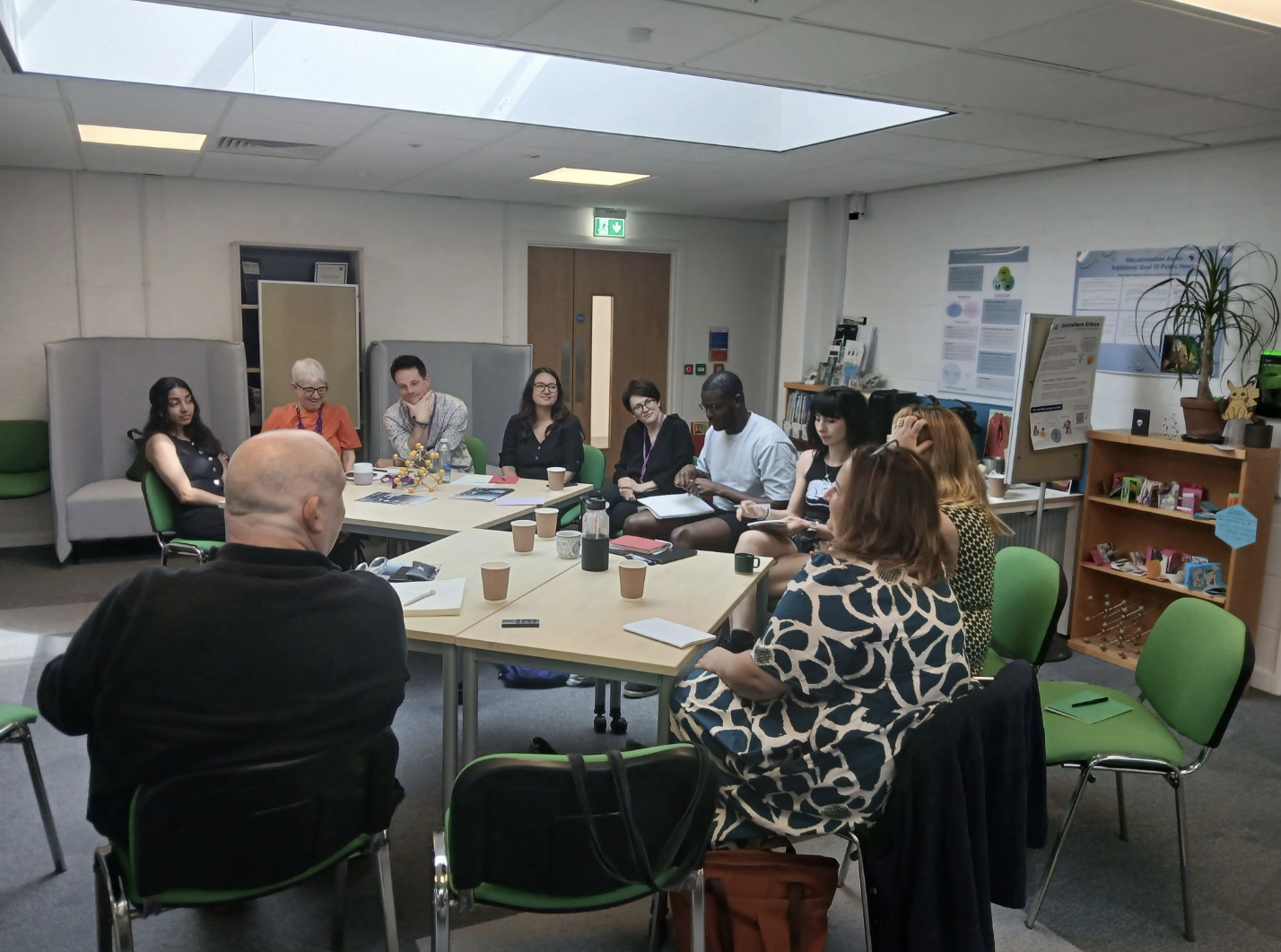 Photograph of a group of people sitting in discussion in an academic institution's room.