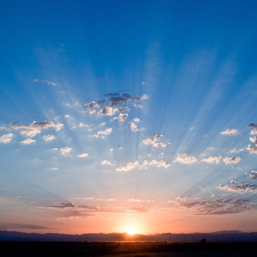 A sunrise over a horizon with some clouds in the sky