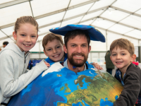 Man dressed up in a world costume surrounded by three children