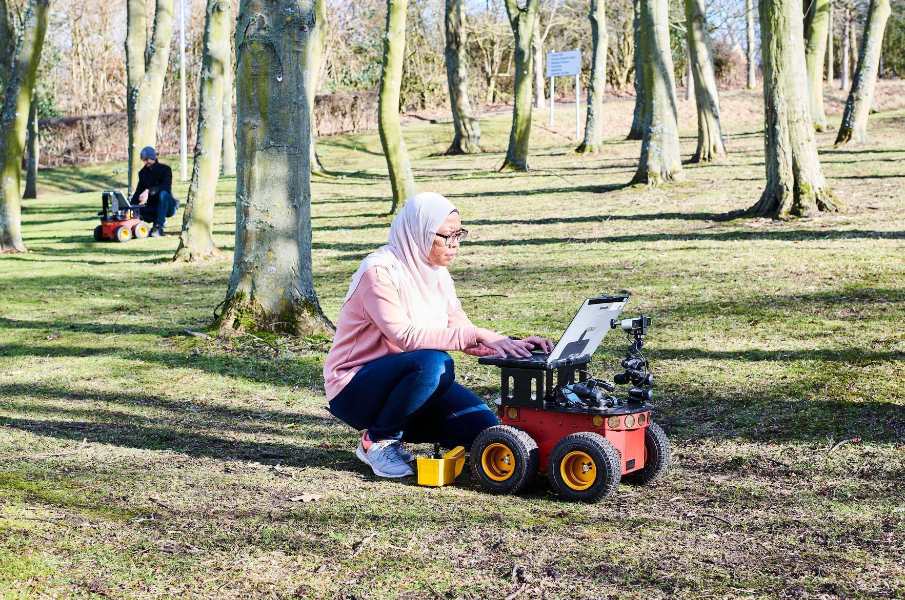 Students working outside on laptops on remote controlled vehicles