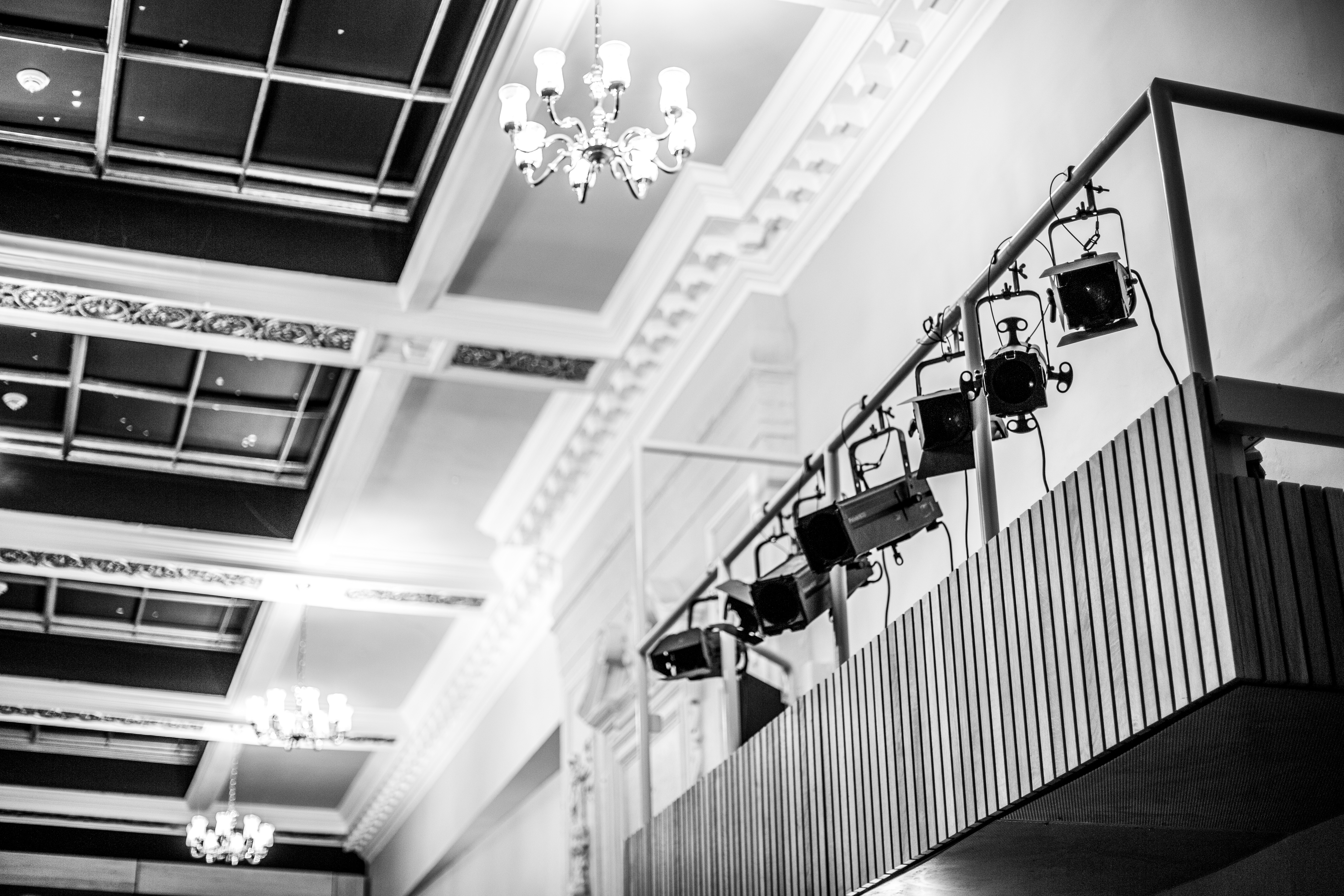 A theatre's ceiling and a bank of stage lights viewed from below in black and white