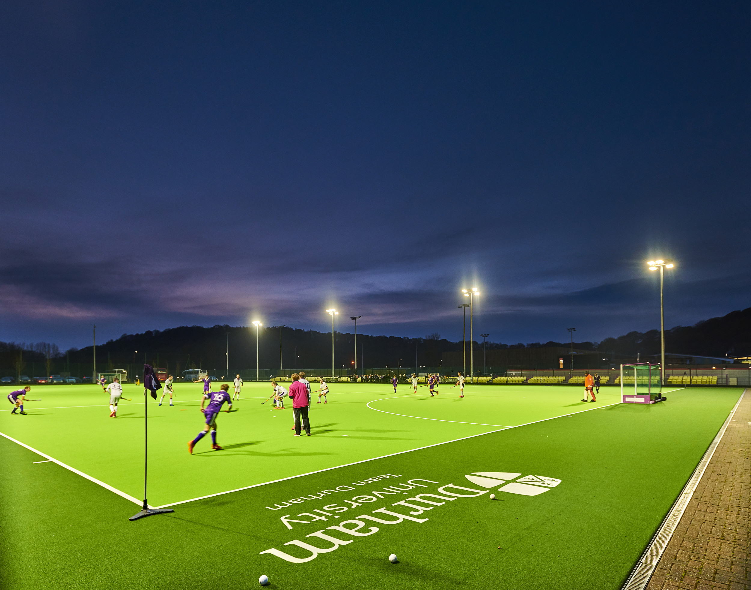 Students playing hockey outdoors on a sports pitch