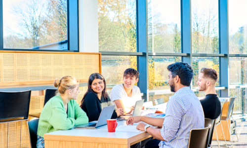 Group of students chatting with laptops at a table