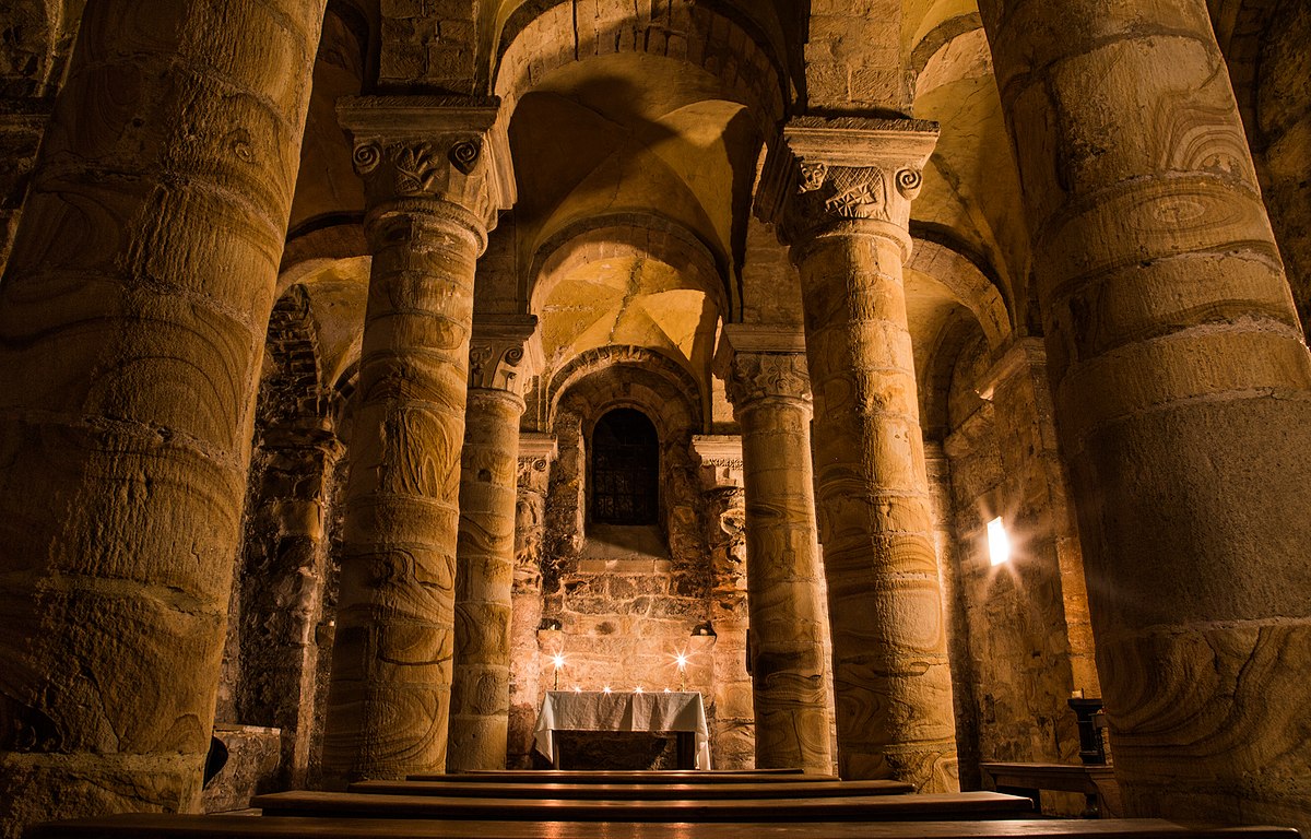 Photograph of the interior of the Norman Chapel at Durham Castle, lit at night by candle-effect lights.