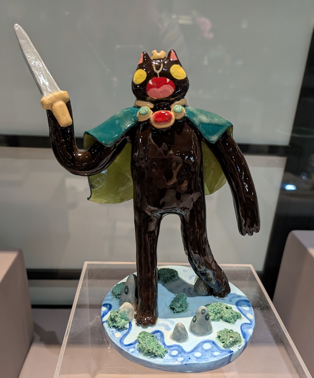 Ceramic figure wearing a blue cloak and holding a sword